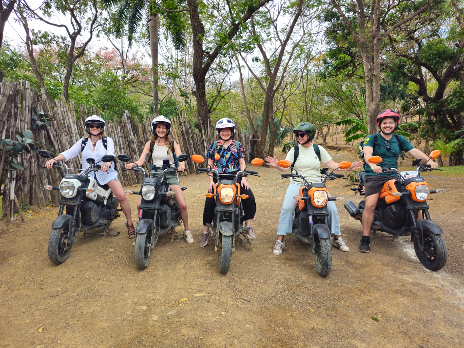 Friends riding Honda Navi scooters down a tropical road in San Juan del Sur